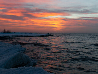 winter landscape from the sea shore, blurred wave slags against frozen ice cubes, blurred sunset color background