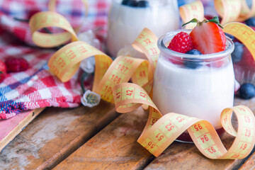 natural yogurt with strawberries and measuring tape, concept of diet and health