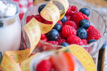 greek yogurt with strawberries and blueberries and measuring tape, diet and health concept