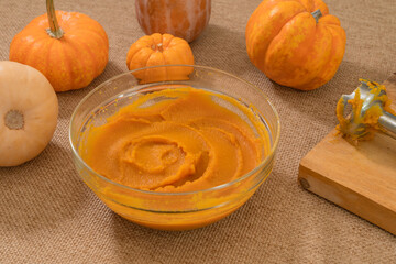 Homemade roasted pumpkin puree from scratch. Fresh puree in a glass bowl close up on kitchen table