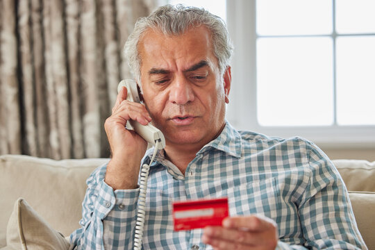 Mature Man At Home Giving Credit Card Details On The Phone