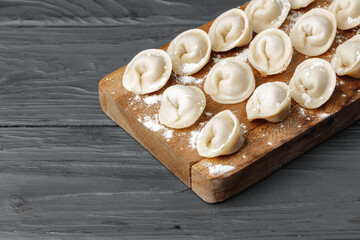 Raw meat dumplings on wooden board on table