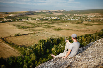 Fototapeta premium Rear view of young man drinking tea or coffee in mountains.