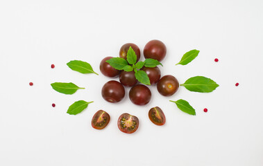 Black cherry tomatoes with basil on white background. Helthy eating and agriculture concept.