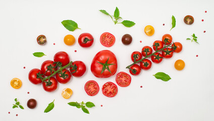 Different kind of tomato and basil creative layout. Various colorful tomatoes and basil leaves on white background.