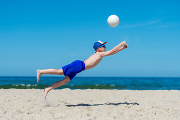 Young boy playing volleyball on beach. Summer sport concept.