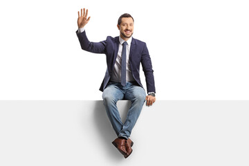 Full length portrait of a man in jeans and tie sitting on a blank panel and waving - obrazy, fototapety, plakaty