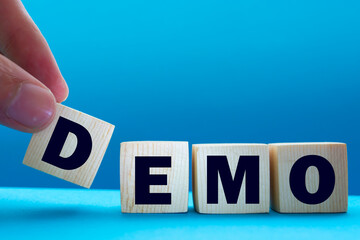 Demo symbol. Concept word 'demo' on cubes on a beautiful dark wooden background. Businessman hand....