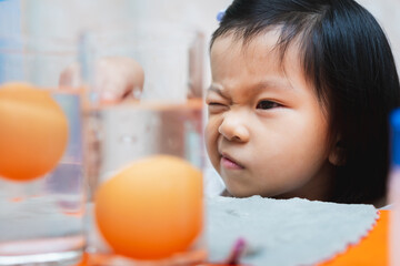 Head shot. Asian child girl is observing science experiment on sinking eggs - floating eggs with...