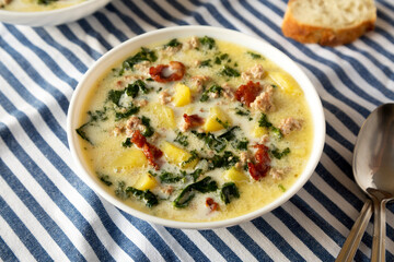 Homemade Zuppa Toscana with Kale and Bread in a white bowl, side view.