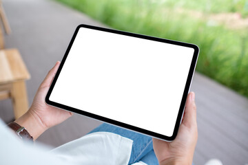 Mockup image of a woman holding digital tablet with blank white desktop screen in the outdoors