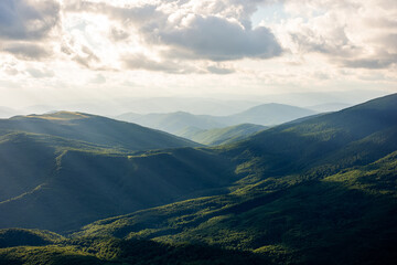 dramatyc mountain landscape in evening light. clouds above the ridge and hills in dappled light. wonderful nature background in summer