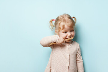 child girl brushing teeth on blue background with copy space