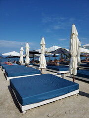 Beach furniture on summer beach. Empty beds and white textile sun shades on beach sand. Luxury coastal vacation