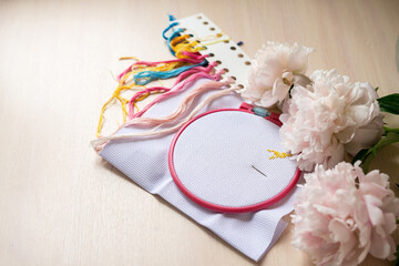 Still life with embroidery set fot cross stitching and vase of peonys. White fabric, embroidery...