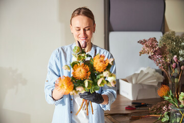 Young woman admiring a beautiful floral arrangement - obrazy, fototapety, plakaty