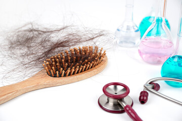 Wooden comb with hair loss blurred stethoscope science test tube background, Solve the problem of hair loss with science, Hair loss problem. Health care concept.	