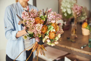 Professional female florist making a beautiful spring bouquet - obrazy, fototapety, plakaty