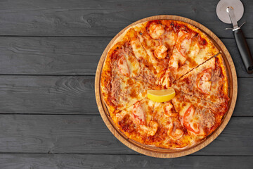 Top view of hot pizza on black wooden table