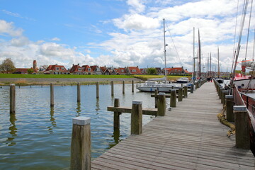 Fototapeta premium The harbor with sailing boats in Makkum, Friesland, Netherlands, and with traditional houses in the background