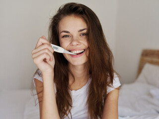 woman with a thermometer in her mouth in the bedroom smile