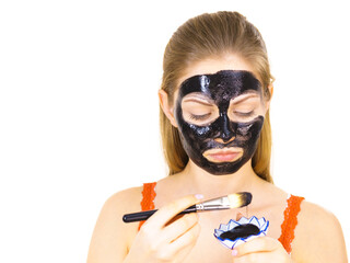 Woman applying black mask to skin face