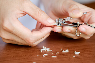 Close-up woman's fingernails are being trimmed with nail clippers. The concept of care, clean...
