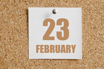 february 23. 23th day of the month, calendar date.White calendar sheet attached to brown cork...