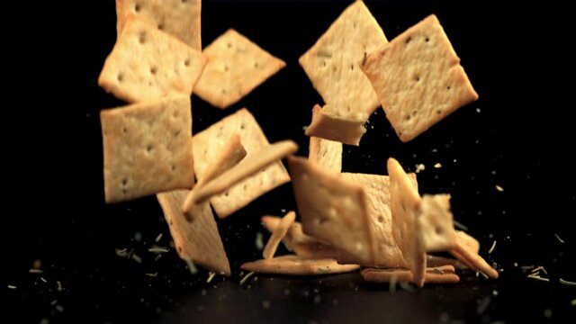 Super slow motion cracker with rosemary falls on the table. On a black background.Filmed on a high-speed camera at 1000 fps.