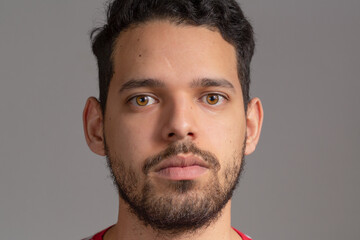 Fototapeta premium Young man frontal extreme closeup portrait in a studio shot, He is latin in his 20s. He is serious.