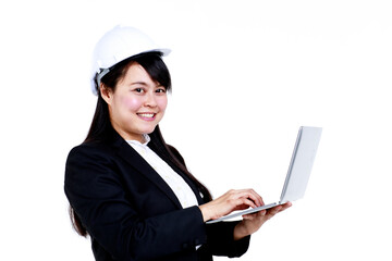 Side view of positive young Asian female construction engineer in black suit and hardhat typing on laptop and looking at camera against white background