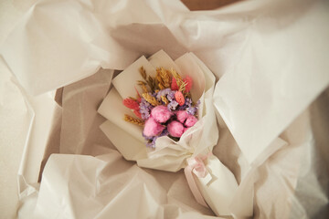 Wrapped bouquet placed on the wrapping paper in a cardboard box
