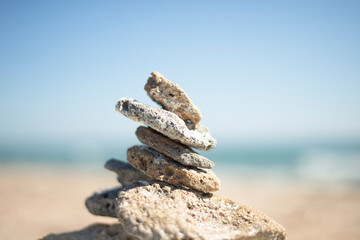 Fototapeta na wymiar A pyramid of stones on the seashore. Cobblestone tower. Conceptual photo. Philosophical themes and themes of body and soul care. Spiritual ideas.