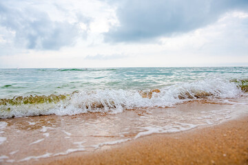 storm on a sandy beach during the day. dramatic ocean scenery with cloudy sky. stormy water and crashing waves in daylight 