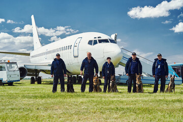 Fototapeta na wymiar Security officers with dogs standing at airfield