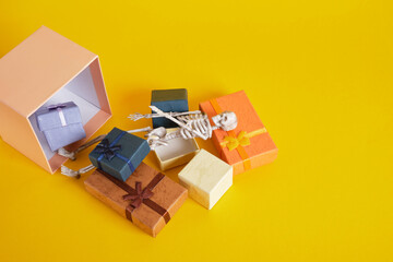 plastic skeleton and gift boxes on yellow background