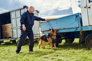 Security officer and drug detection dog checking truck at aerodrome