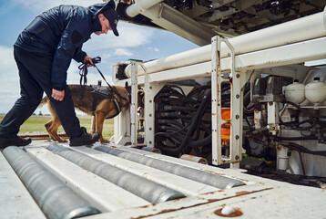 Security officer and detection dog inspecting plane at aerodrome