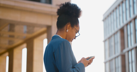 African young businesswoman wearing suit using smartphone in city