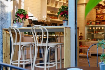 Cozy cafe with seats outside. White high chairs and flowers
