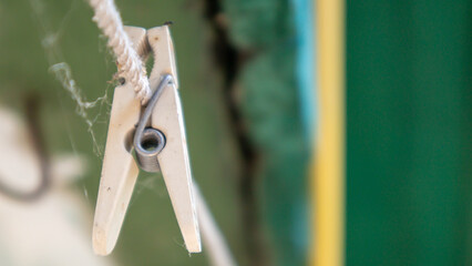Plastic clothespins hang in a row on the rope. Rope outdoors, on a blurred background in a sunny garden. Clothesline on the street. Clothespins.