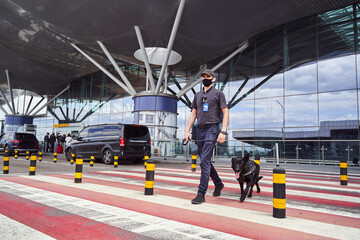 Security officer with detection dog crossing the road at airport