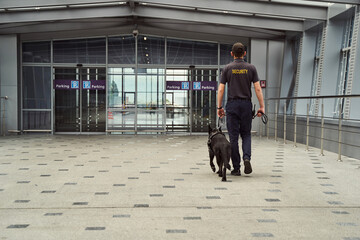 Security officer with police dog heading to parking building