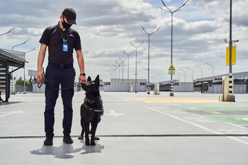 Security officer and police dog patrolling territory of airport