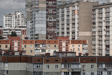 Fototapeta premium Cityscape of a stuffy post-Soviet city, densely built up with multi-storey residential panel buildings in red and white colors.