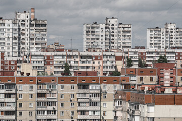 Cityscape of a stuffy post-Soviet city, densely built up with multi-storey residential panel buildings in red and white colors.
