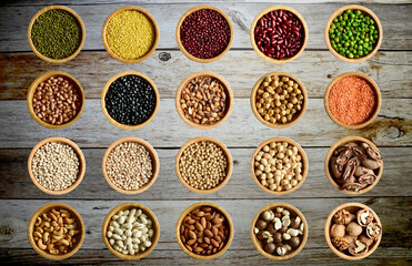 Top Views of 20 Assortment of Nuts in a wooden Bowls isolated on wooden background, Healthy Food Concept.
