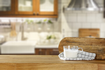 Fresh milk in glass on wooden table and kitchen interior 