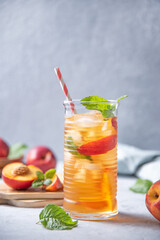 cool peach tea with mint and ice in a glass on a blue background. Vertical orientation.  Front view and copy space