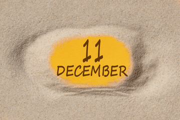 December 11. 11th day of the month, calendar date. Hole in sand. Yellow background is visible through hole. Winter month, day of the year concept